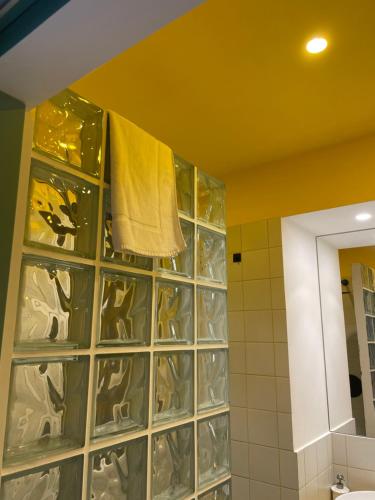 a bathroom with a glass block wall with a yellow towel at Dusmè in Taranto