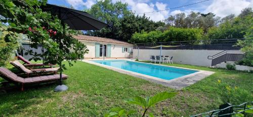 a backyard with a swimming pool and an umbrella at Bienvenue à L'ÉCRIN avec piscine privée in LʼIsle-sur-la-Sorgue