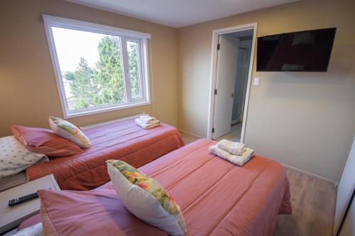 um quarto com três camas e uma televisão e uma janela em Departamentos Avenida Colon em Punta Arenas
