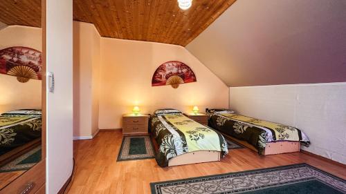 sypialnia z 2 łóżkami i drewnianym sufitem w obiekcie Napfény vendégház w Győr