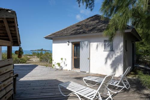 dos sillas sentadas en una terraza junto a un edificio en Chez Cay Cottage cottage, en Governorʼs Harbour