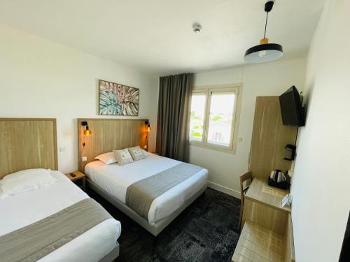 um quarto de hotel com duas camas e uma janela em Logis Le Passiflore Cognac em Châteaubernard