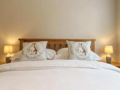 a bed with two pillows with portraits of dogs on them at The Stables at Hall Barn in Diss