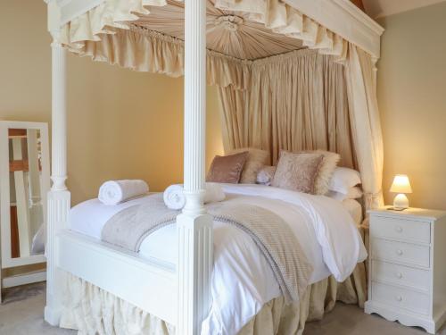 a bedroom with a canopy bed with white sheets and pillows at The Stables at Hall Barn in Diss