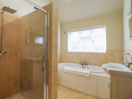 a bathroom with a shower and a tub and a sink at The Stables at Hall Barn in Diss
