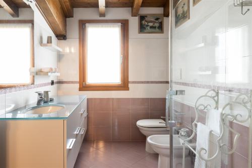 La salle de bains est pourvue de toilettes, d'un lavabo et d'une douche. dans l'établissement IseoLakeRental - Casa Giovannina, à Paratico