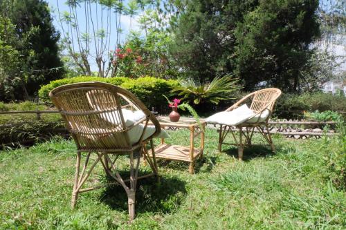 two wicker chairs and a table in the grass at Sambodhi Yoga Home in Kathmandu