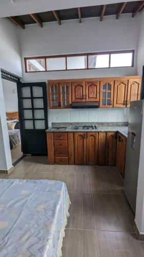 a kitchen with wooden cabinets and a bed in a room at UKU INN in Medellín