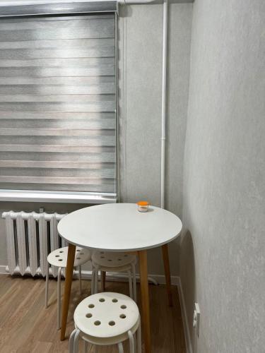 アルマトイにあるКвартира в микрорайоне Коктем 3の窓前白いテーブルと椅子2脚