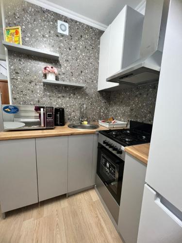 een kleine keuken met witte kasten en een wastafel bij Квартира в микрорайоне Коктем 3 in Alma-Ata