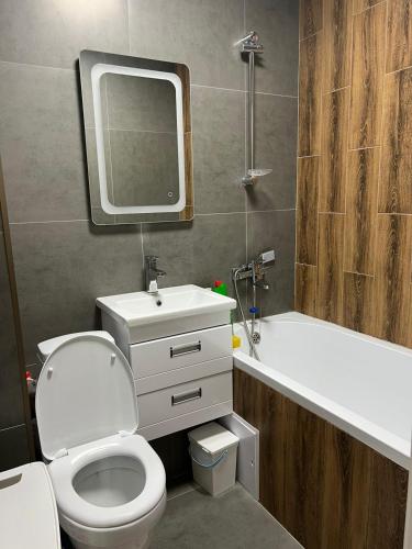 a bathroom with a toilet and a sink and a mirror at Квартира в микрорайоне Коктем 3 in Almaty