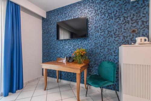 a room with a table and a television on a blue wall at Hotel Ancora in Pontecagnano