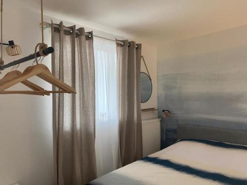 Schlafzimmer mit einem Bett und einem Fenster mit einem Spiegel in der Unterkunft Appartement cosy Le Saint Gildas, à proximité immédiate centre ville, place de stationnement, Netflix in Vannes