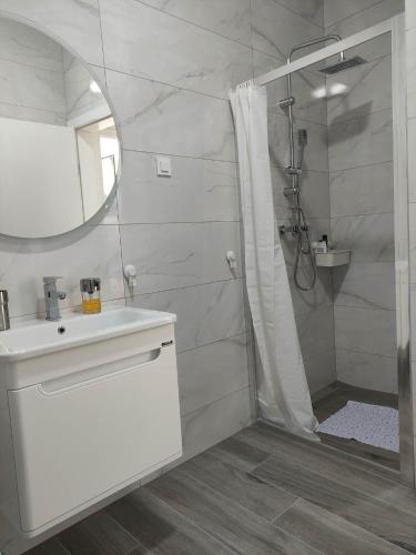 a white bathroom with a shower and a sink at Apartman Waldy in Osijek