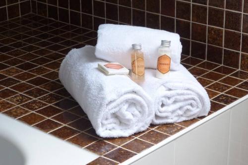 ein Badezimmer mit weißen Handtüchern und 2 Flaschen Shampoo in der Unterkunft Crac’h, grande maison de vacances au calme in Crach