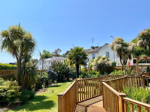 a wooden walkway in a yard with palm trees and houses at Bentley Lodge in Torquay
