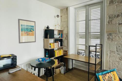 ein Wohnzimmer mit einem Tisch und einem Bücherregal in der Unterkunft Corner cocoon in the center of La Rochelle in La Rochelle