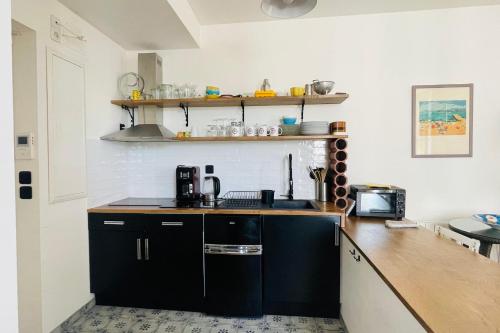 une cuisine avec des armoires noires et un comptoir dans l'établissement Corner cocoon in the center of La Rochelle, à La Rochelle