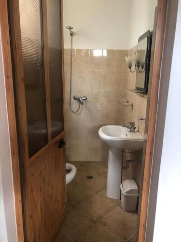 a bathroom with a sink and a toilet and a door at Roni’s apartment in Lezhë