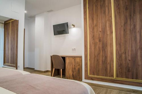 1 dormitorio con escritorio y TV en la pared en HOTEL RURAL LA TEJA, en Segura de León