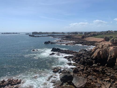 a rocky shoreline with the ocean and the water at Maison Caroual Erquy 500m de la PLAGE in Erquy