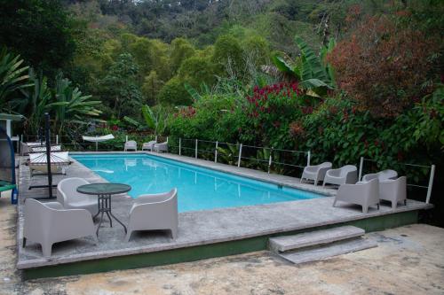 a swimming pool with white chairs and a table and a table and chairs at HOTEL CERVECERIA JAMES in Xilitla