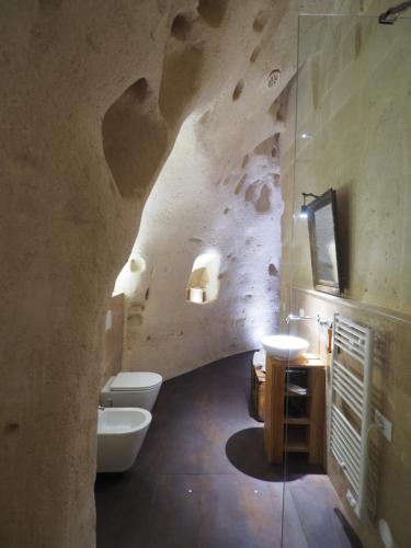 a bathroom with two toilets and a stone wall at Dimore dei Mercanti in Matera
