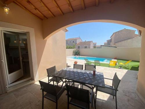 un patio avec une table et des chaises et une piscine dans l'établissement Birds Villa, piscine chauffée, clim, garage, wifi, à Arles