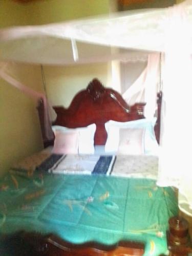 1 cama con cabecero de madera en una habitación en City Max hotel Kabaale, en Kabale