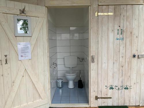 a bathroom with a toilet and a wooden door at mongolische Jurte im ART.Quartier in Velgast