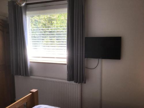 a bedroom with a flat screen tv on the wall next to a window at City apartment no.8 in Norwich