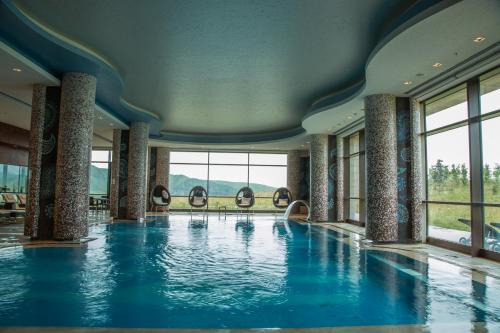 a swimming pool with blue water in a building with windows at Shahdag Hotel & Spa in Shahdag
