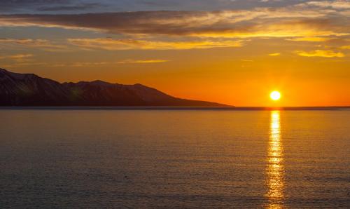 a sunset over the water with mountains in the background at Tungulending Guesthouse in Tungulending