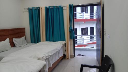 - une chambre avec un lit et une fenêtre avec des rideaux bleus dans l'établissement Hotel Arindam, à Phata