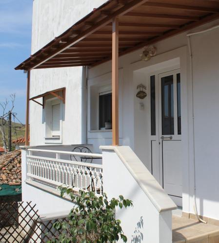 a white house with a porch and a deck at Dabia Apartments in Mirina