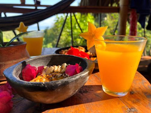 a bowl of food and a glass of orange juice at Finca La Selvita in Buritaca