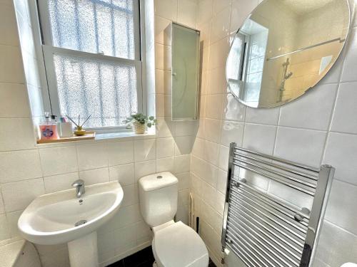 uma casa de banho com um WC, um lavatório e um espelho. em Archway Station Big Bedroom Flat em Londres