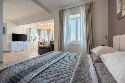 a bedroom with a large bed and a living room at Apartments Villa Dora in Kraljevica