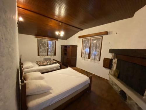 Jaujac的住宿－NOUVEAU Maison de la place，一间卧室设有两张带白色床单和木制天花板的床。