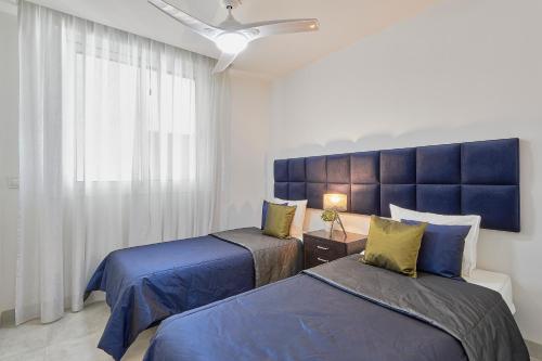 a bedroom with two beds and a blue headboard at Casa Banderas, Sea View at Luxury complex in La Cala de Mijas