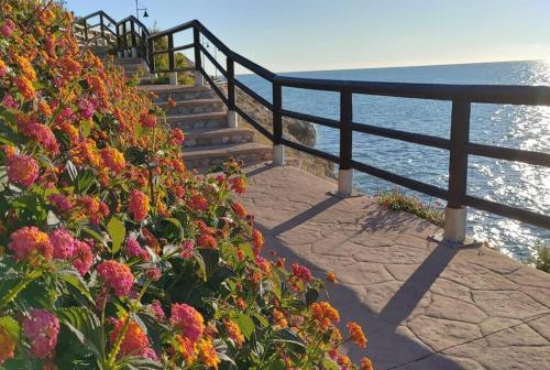 un conjunto de escaleras junto al océano con flores en Casa Chema I - Apartamento/Parking/Piscina/Playa, en Cala del Moral