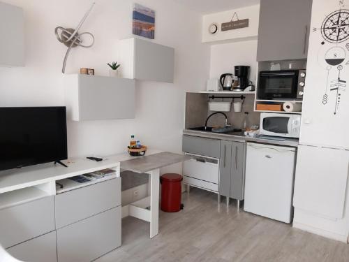 Il comprend une cuisine avec des placards blancs et un bureau avec une télévision. dans l'établissement Studio Cosy en hyper centre, à Arcachon