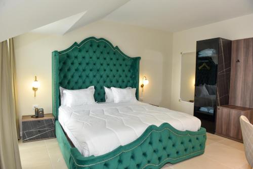 a bedroom with a large bed with a green headboard at Hotel Royal in Shkodër