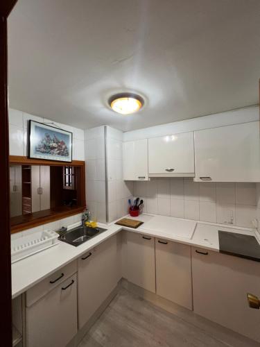 uma cozinha branca com armários brancos e um lavatório em Apartamento kuki en Rincón de Loix em Benidorm