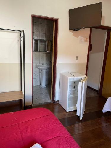 a room with a bed and a refrigerator and a sink at POUSADA PARLATORIUM in Tiradentes