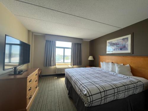 a hotel room with a bed and a flat screen tv at Wingate by Wyndham Coon Rapids in Coon Rapids