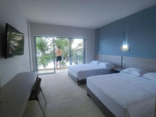 a bedroom with two beds and a man walking out the window at Hotel Rilux Tolu in Tolú