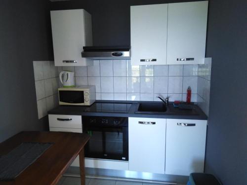 una cocina con armarios blancos y horno negro en Lux apartman, en Žuljana