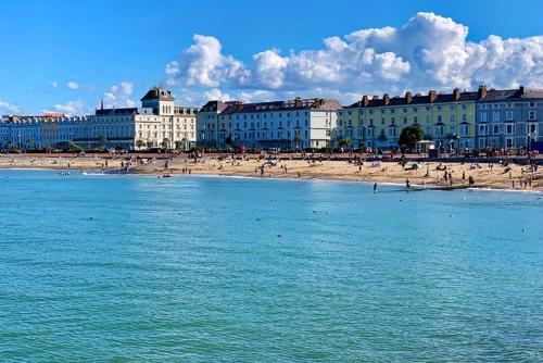 a beach with buildings and people on the beach at Elsinore Hotel Llandudno in Llandudno