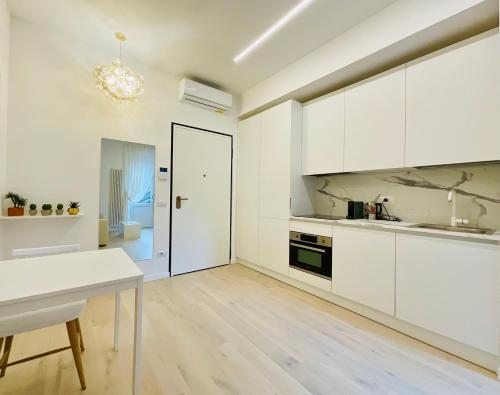 a white kitchen with white cabinets and a table at Apartment Suite - Charlize - in the heart of Milan in Milan